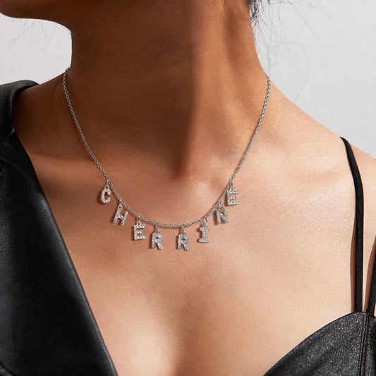 Necklace with 'CHERISH' pendant on a person wearing a black top.