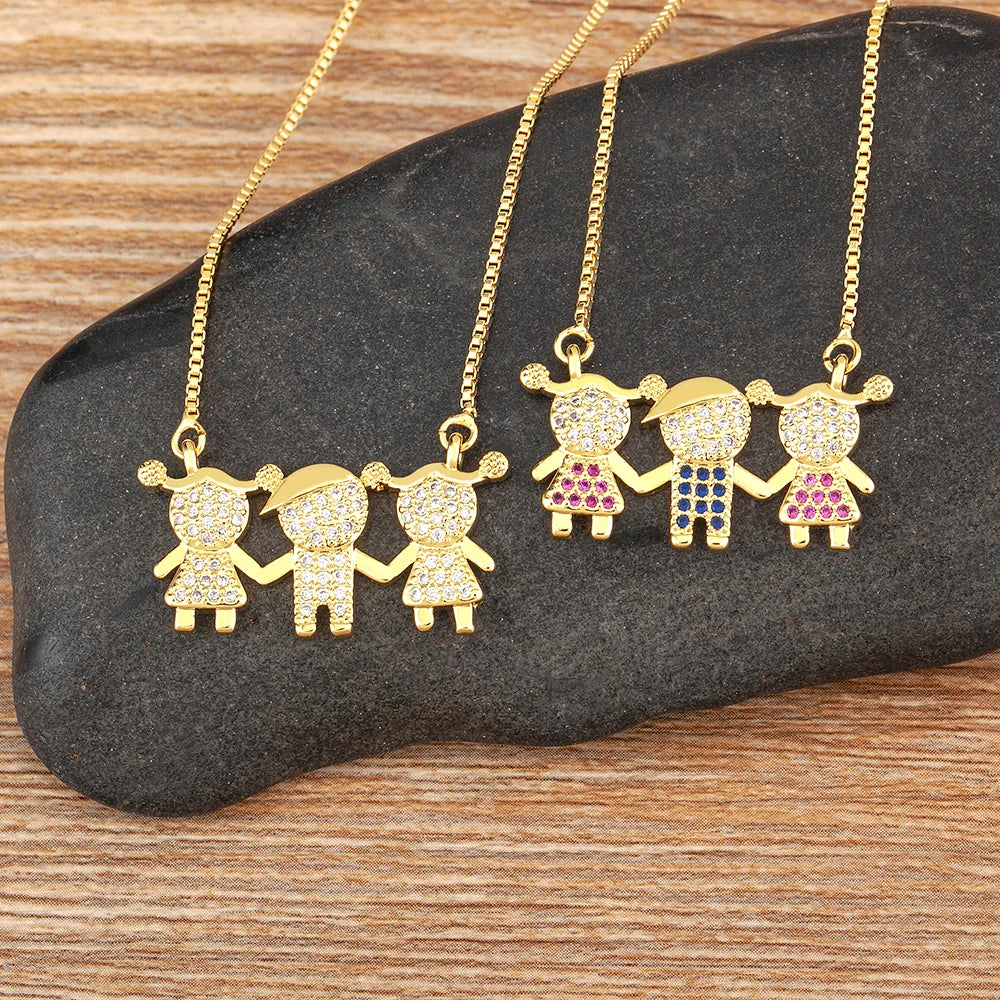 Gold necklaces with family-themed pendants on a dark stone surface