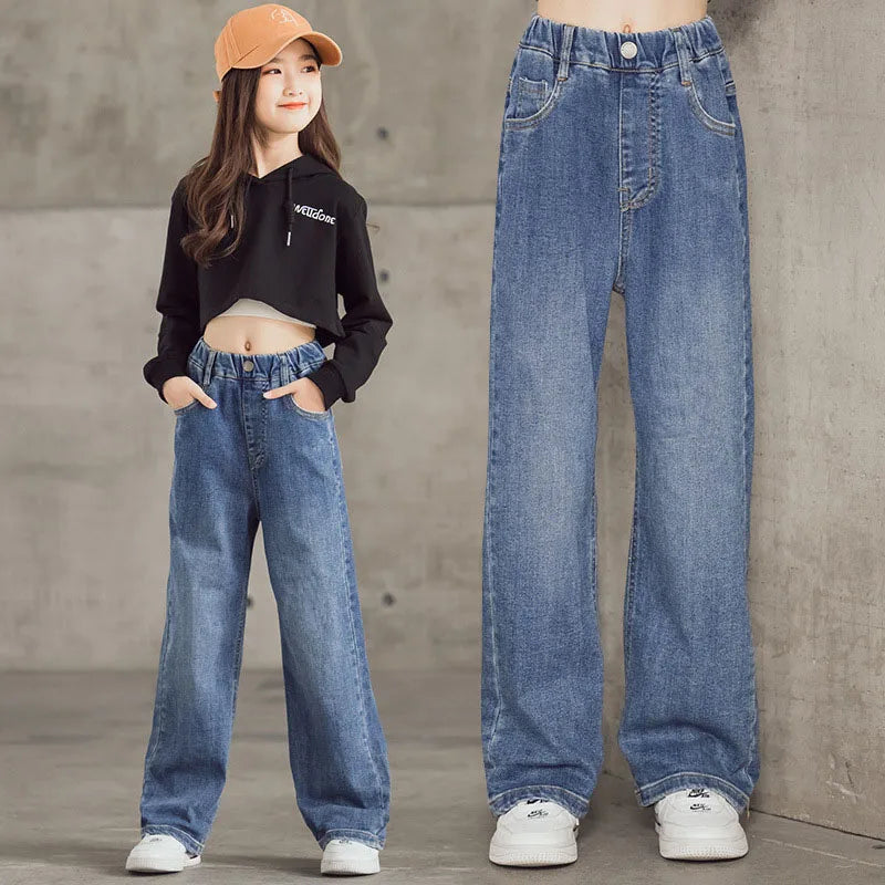 Person wearing high-waisted blue jeans with a concrete wall backgroun