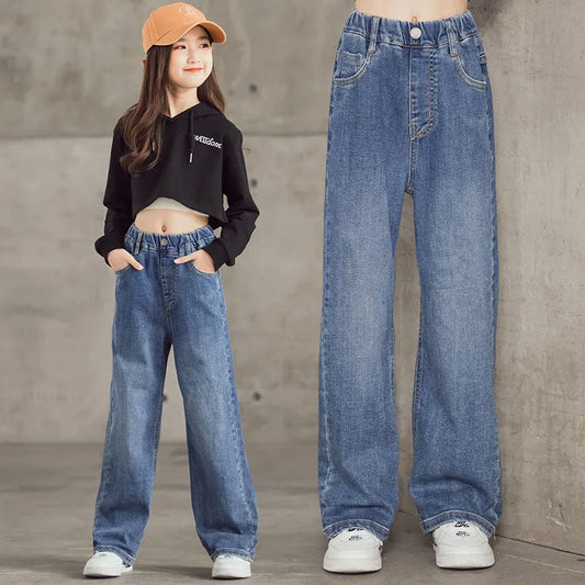 Person wearing high-waisted blue jeans with a concrete wall backgroun
