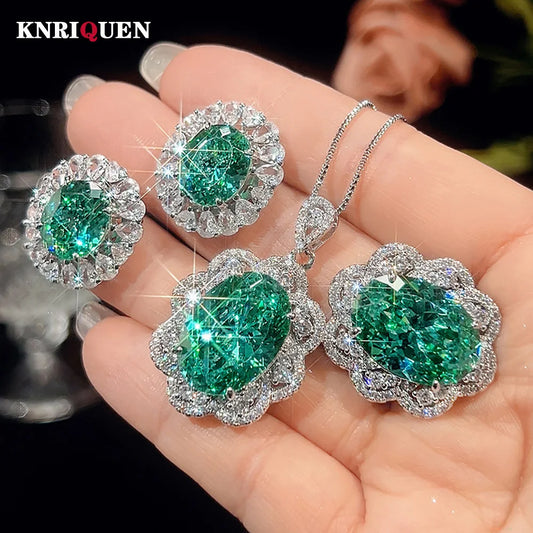 Emerald and diamond jewelry set held in a hand with 'KNRIQUEN' branding.