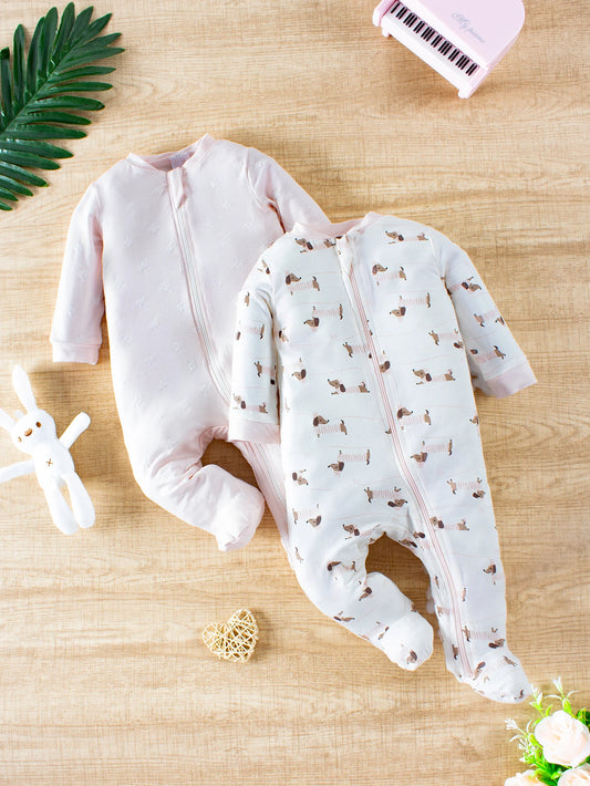 Two baby onesies on a wooden surface with decorative elements.